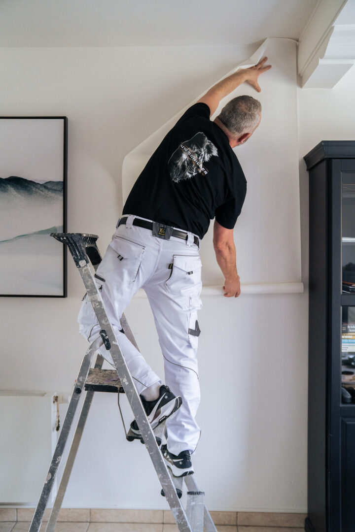 Pieter hangt een baan behang op
