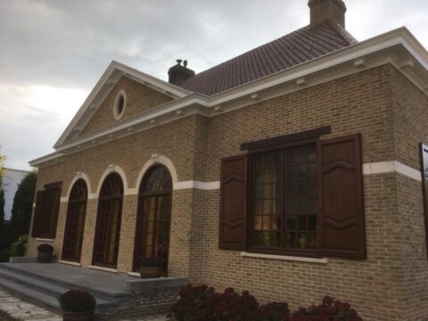 Bakstenen woning met geschilderde ramen en luiken
