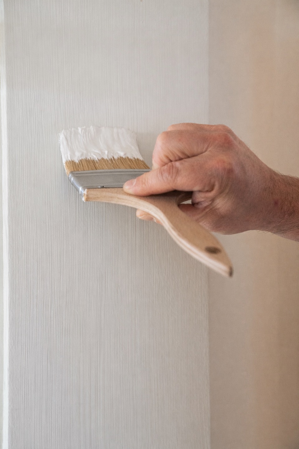 Penseel met witte verf op een strak geschilderde wand