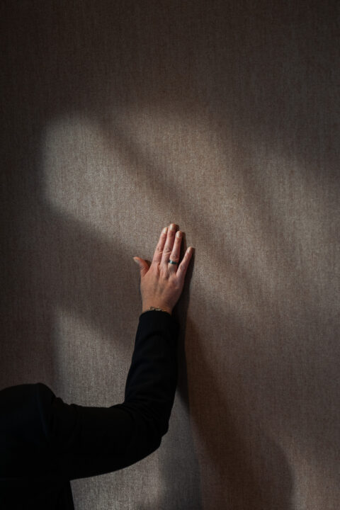 Hand op een wand met textielachtige wandbekleding